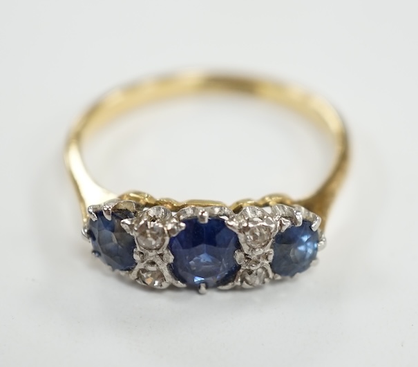 An 18ct and plat. three stone sapphire and four stone diamond chip spacer set ring, size N/O, gross weight 3.2 grams. Condition - poor to fair